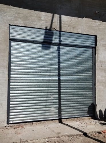 Cortina metálica con paño superior instalada en el hueco de una pared de hormigón